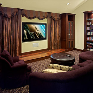 Réalisation d'une salle de cinéma tradition de taille moyenne avec un mur jaune, moquette, un téléviseur encastré et un sol multicolore.