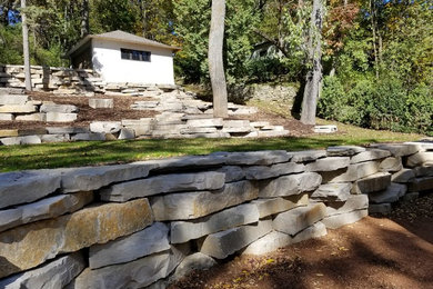 Design ideas for a mid-sized rustic hillside retaining wall landscape in Milwaukee.