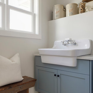 This is an example of a medium sized modern separated utility room in Minneapolis with a belfast sink, beaded cabinets, blue cabinets, beige walls, painted wood flooring, a side by side washer and dryer and white floors.