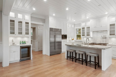 Huge beach style u-shaped kitchen photo in New York with white cabinets, quartzite countertops, stainless steel appliances and an island