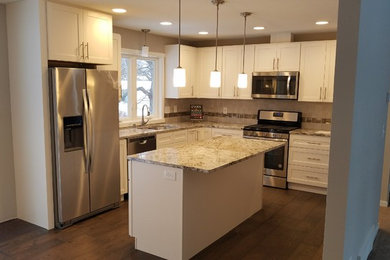 Inspiration for a mid-sized timeless l-shaped dark wood floor and brown floor open concept kitchen remodel in Minneapolis with a double-bowl sink, recessed-panel cabinets, white cabinets, granite countertops, beige backsplash, stone tile backsplash, stainless steel appliances, an island and beige countertops