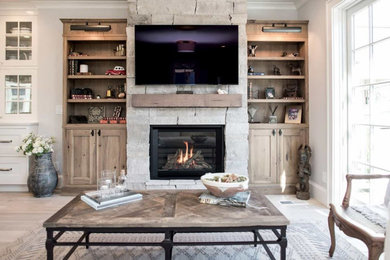 Mid-sized mountain style light wood floor and beige floor living room photo in Seattle with white walls, a standard fireplace, a stone fireplace and a wall-mounted tv