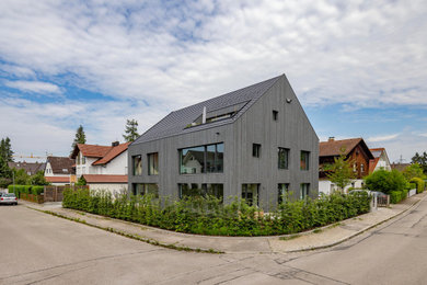 Große, Zweistöckige Moderne Holzfassade Haus mit grauer Fassadenfarbe, Satteldach, Ziegeldach, grauem Dach und Verschalung in München