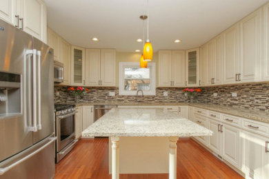 Open concept kitchen - mid-sized transitional u-shaped medium tone wood floor open concept kitchen idea in Chicago with an undermount sink, raised-panel cabinets, white cabinets, granite countertops, multicolored backsplash, matchstick tile backsplash, stainless steel appliances and an island