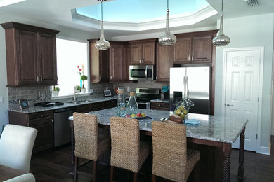 Eat-in kitchen - mid-sized contemporary l-shaped dark wood floor and brown floor eat-in kitchen idea in San Diego with a double-bowl sink, raised-panel cabinets, dark wood cabinets, granite countertops, beige backsplash, ceramic backsplash, stainless steel appliances, an island and gray countertops