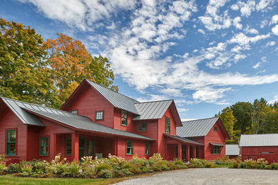 На фото: деревянный, красный частный загородный дом в стиле кантри с двускатной крышей, металлической крышей и отделкой планкеном с