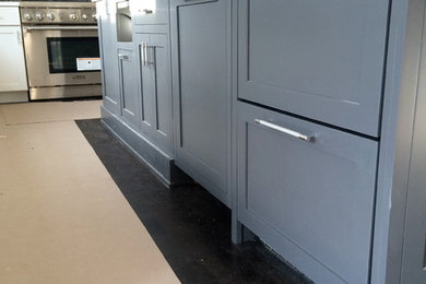 Kitchen - mid-sized transitional l-shaped dark wood floor kitchen idea in New York with shaker cabinets, gray cabinets, solid surface countertops, gray backsplash, stone tile backsplash, stainless steel appliances and an island