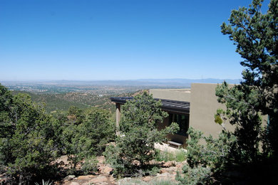 This is an example of a mid-sized contemporary split-level stucco green exterior in Albuquerque with a flat roof.