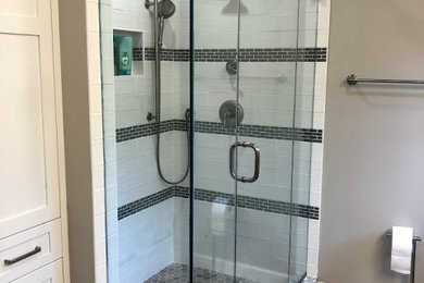 Mid-sized transitional master white tile and ceramic tile porcelain tile, brown floor and double-sink bathroom photo in Baltimore with shaker cabinets, white cabinets, a one-piece toilet, gray walls, an undermount sink, quartz countertops, a hinged shower door, multicolored countertops and a freestanding vanity