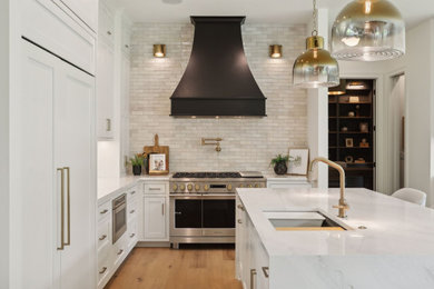 Example of a large transitional l-shaped medium tone wood floor kitchen design in Minneapolis with an undermount sink, flat-panel cabinets, white cabinets, quartz countertops, white backsplash, ceramic backsplash, an island and white countertops