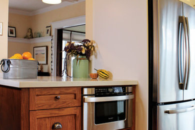 Inspiration for a mid-sized craftsman u-shaped medium tone wood floor eat-in kitchen remodel in Toronto with a farmhouse sink, recessed-panel cabinets, medium tone wood cabinets, quartz countertops, white backsplash, subway tile backsplash, stainless steel appliances and a peninsula