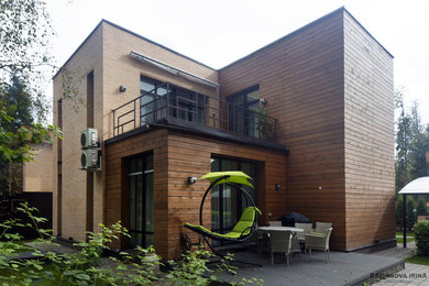 На фото: двухэтажный, деревянный, коричневый дом среднего размера в стиле неоклассика (современная классика) с плоской крышей