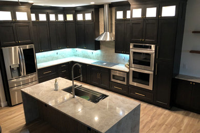 Huge trendy galley light wood floor, beige floor and tray ceiling open concept kitchen photo in Other with an undermount sink, shaker cabinets, dark wood cabinets, quartz countertops, white backsplash, quartz backsplash, stainless steel appliances, an island and beige countertops