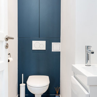 Esempio di un piccolo bagno di servizio minimalista con ante a filo, ante blu, WC sospeso, piastrelle bianche, pareti blu, pavimento in cementine, lavabo sospeso, top in superficie solida, pavimento grigio e top bianco