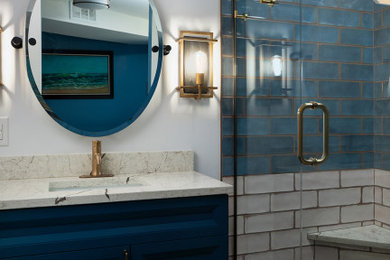 This is an example of a medium sized traditional shower room bathroom in Denver with freestanding cabinets, blue cabinets, an alcove shower, a two-piece toilet, blue tiles, ceramic tiles, blue walls, wood-effect flooring, a submerged sink, engineered stone worktops, beige floors, a hinged door, a shower bench, a single sink and a freestanding vanity unit.