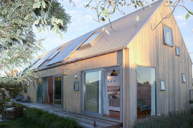 Example of a small trendy two-story wood exterior home design in Christchurch with a metal roof