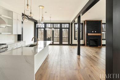 Inspiration for a large transitional l-shaped light wood floor and brown floor open concept kitchen remodel in Philadelphia with an undermount sink, shaker cabinets, white cabinets, quartz countertops, white backsplash, porcelain backsplash, stainless steel appliances, an island and white countertops