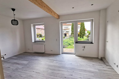Mittelgroße Moderne Wohnküche mit weißer Wandfarbe, Laminat, grauem Boden, freigelegten Dachbalken und Wandgestaltungen in Hannover