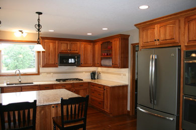 Mid-sized elegant l-shaped dark wood floor eat-in kitchen photo in Other with a double-bowl sink, raised-panel cabinets, dark wood cabinets, granite countertops, beige backsplash, ceramic backsplash, stainless steel appliances and an island