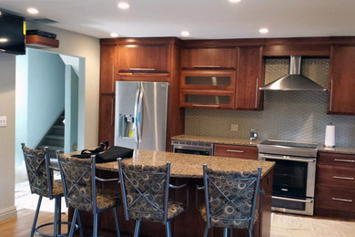 Example of a minimalist l-shaped light wood floor open concept kitchen design in New York with raised-panel cabinets, dark wood cabinets, granite countertops, glass tile backsplash, stainless steel appliances and an island