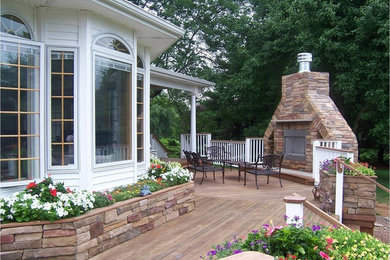 Large transitional backyard deck in Other with a fire feature and a roof extension.