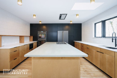 Mid-sized minimalist u-shaped light wood floor and brown floor eat-in kitchen photo in New York with an undermount sink, flat-panel cabinets, black cabinets, concrete countertops, white backsplash, ceramic backsplash, stainless steel appliances, an island and gray countertops