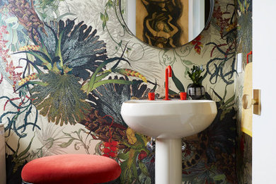 Inspiration for a mid-sized eclectic powder room in Los Angeles with light hardwood floors, a pedestal sink and wallpaper.