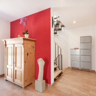 Exempel på en mellanstor klassisk hall, med röda väggar, klinkergolv i terrakotta och brunt golv