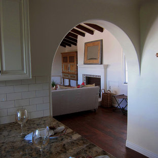 Diseño de salón cerrado, mediterráneo, pequeño, sin televisor, con paredes blancas, suelo de madera en tonos medios, chimenea tradicional, marco de chimenea de baldosas y/o azulejos y suelo marrón