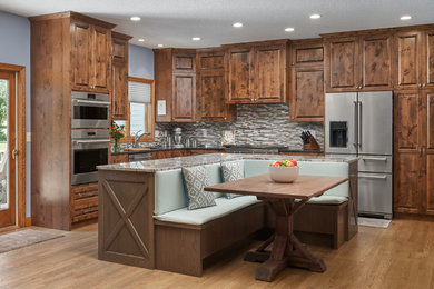 Traditional eat-in kitchen in Minneapolis with an undermount sink, raised-panel cabinets, dark wood cabinets, mosaic tile splashback, stainless steel appliances, medium hardwood floors, with island, brown floor, multi-coloured benchtop and multi-coloured splashback.