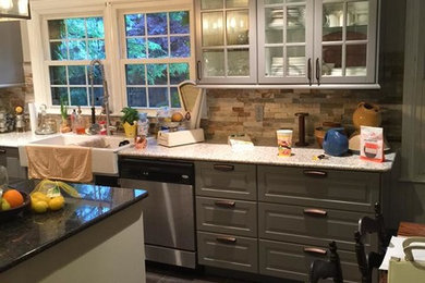Example of a large mid-century modern l-shaped cement tile floor eat-in kitchen design in Indianapolis with a farmhouse sink, raised-panel cabinets, gray cabinets, granite countertops, beige backsplash, brick backsplash, stainless steel appliances and an island