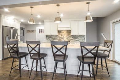 Inspiration for a large coastal galley dark wood floor and brown floor open concept kitchen remodel in Milwaukee with an undermount sink, recessed-panel cabinets, white cabinets, quartz countertops, multicolored backsplash, stone tile backsplash, stainless steel appliances, an island and multicolored countertops