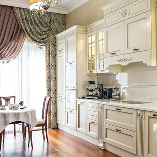 Ejemplo de cocina comedor en L, tradicional, grande, sin isla, con encimera de acrílico, salpicadero de azulejos de cerámica, electrodomésticos blancos, suelo de madera en tonos medios, suelo marrón, armarios estilo shaker, puertas de armario blancas y salpicadero blanco