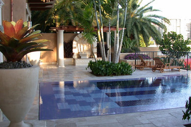 Photo of a tropical rectangular pool in Miami with natural stone pavers.
