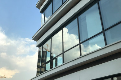 Imagen de fachada blanca moderna de una planta con revestimiento de vidrio y tejado plano
