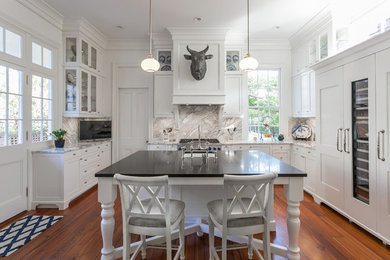 Kitchen - traditional u-shaped dark wood floor kitchen idea in Charleston with an undermount sink, shaker cabinets, white cabinets, white backsplash, paneled appliances and an island