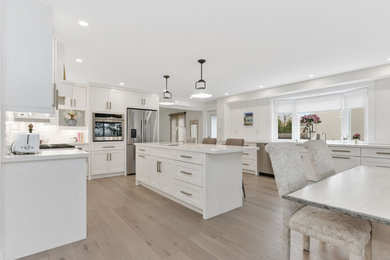 Inspiration for a large light wood floor and brown floor eat-in kitchen remodel in DC Metro with shaker cabinets, white cabinets, marble countertops, white backsplash, an island, white countertops, granite backsplash and stainless steel appliances