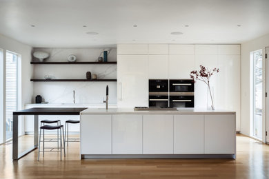 Immagine di una grande cucina minimalista con lavello sottopiano, ante bianche, paraspruzzi bianco, paraspruzzi in gres porcellanato e top bianco