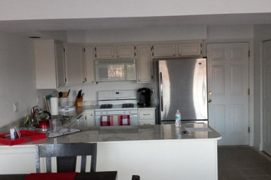 Example of a l-shaped linoleum floor and brown floor eat-in kitchen design in Other with a double-bowl sink, raised-panel cabinets, white cabinets, laminate countertops, a peninsula and white countertops