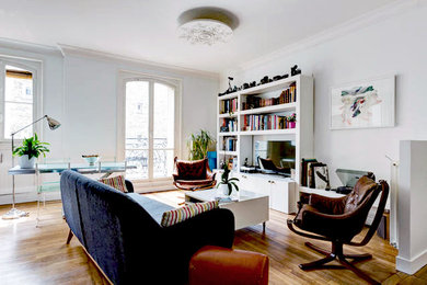 Réalisation d'un petit salon minimaliste avec un mur bleu, un sol en bois brun, aucune cheminée, un téléviseur dissimulé et un sol marron.