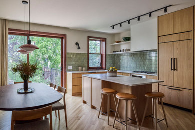 Eat-in kitchen - mid-sized 1950s l-shaped light wood floor and brown floor eat-in kitchen idea in New York with an undermount sink, flat-panel cabinets, light wood cabinets, marble countertops, green backsplash, ceramic backsplash, paneled appliances, an island and white countertops