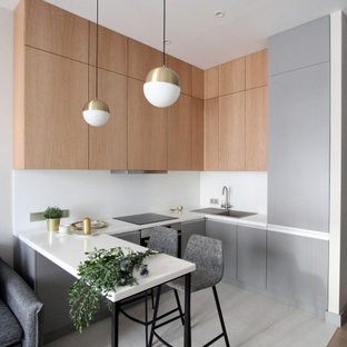 Стильный дизайн: п-образная кухня в современном стиле с плоскими фасадами, светлыми деревянными фасадами, белым фартуком, серым полом и белой столешницей - последний тренд