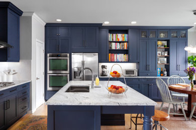 Mid-sized transitional l-shaped medium tone wood floor and brown floor eat-in kitchen photo in Raleigh with an undermount sink, recessed-panel cabinets, blue cabinets, granite countertops, white backsplash, ceramic backsplash, stainless steel appliances, an island and white countertops