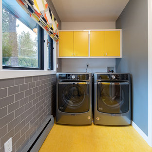 Midcentury separated utility room in Other with flat-panel cabinets, yellow cabinets, grey walls, a side by side washer and dryer and yellow floors.