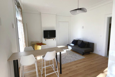 Diseño de salón abierto y blanco y madera contemporáneo de tamaño medio con paredes blancas, suelo laminado, suelo marrón y machihembrado