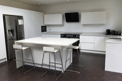 Medium sized contemporary u-shaped open plan kitchen in Hertfordshire with flat-panel cabinets and an island.