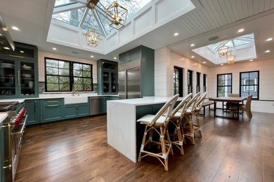 Open concept kitchen - large transitional u-shaped medium tone wood floor, brown floor and shiplap ceiling open concept kitchen idea in Providence with a farmhouse sink, beaded inset cabinets, green cabinets, quartz countertops, gray backsplash, stone tile backsplash, stainless steel appliances, a peninsula and white countertops
