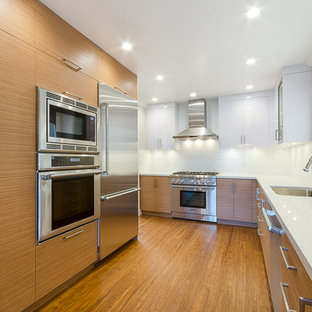 Inspiration for a medium sized modern u-shaped enclosed kitchen in San Francisco with a submerged sink, flat-panel cabinets, white cabinets, white splashback, stainless steel appliances, light hardwood flooring, no island, engineered stone countertops and beige floors.