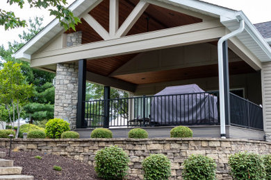 This is an example of a large concrete metal railing back porch design in St Louis with a fireplace and a roof extension.