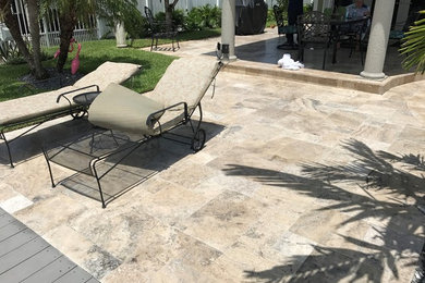 Photo of a large contemporary backyard rectangular aboveground pool in Miami with natural stone pavers.
